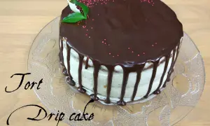 Pyszny tort drip cake z czekoladą spływającą po bokach, ozdobiony różową posypką i listkami.