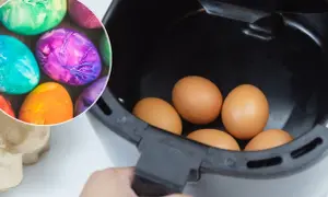 Kolorowe jajka wielkanocne obok surowych jajek w airfryerze.