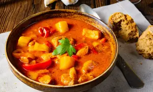 Aksamitna zupa gulaszowa przepis babci, pełna mięsa, ziemniaków i papryki, podana z chlebem.