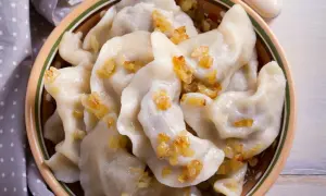 Pyszne pierogi chłopskie, okraszone skwarkami, w glinianej misie.