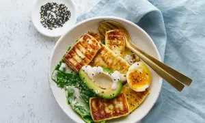 Szybki obiad keto: grillowany ser halloumi, awokado, jajko na miękko i zielone liście, posypane czarnym sezamem.