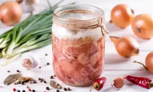 Słoik z domową kiełbasą w galarecie, obok cebula, czosnek, pieprz i chili. Idealny przepis na to, jak zrobić kiełbasę w słoiku z galaretką.