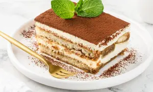Pyszny kawałek tiramisu z mascarpone, posypany kakao i udekorowany miętą. Idealny na deser, gdy szukasz sprawdzonego przepisu.