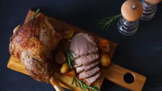 Pieczona jagnięcina, co to za przysmak! Soczyste mięso, chrupiące ziemniaczki i rozmaryn na drewnianej desce.