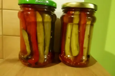 Dwa słoiki domowych pikli z ogórków słodko-kwaśnych z papryką.