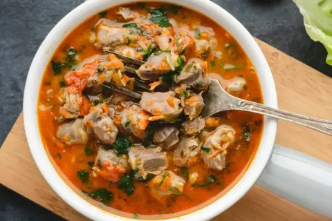 Gulasz z żołądków drobiowych, bardzo dobry przepis. Aromatyczne danie z kawałkami mięsa, marchewką i natką pietruszki w sosie pomidorowym.