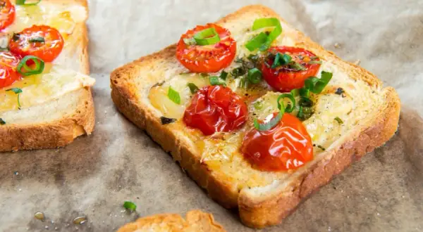 Pyszna, lekka kolacja: tosty z roztopionym serem, pieczonymi pomidorkami koktajlowymi i szczypiorkiem.