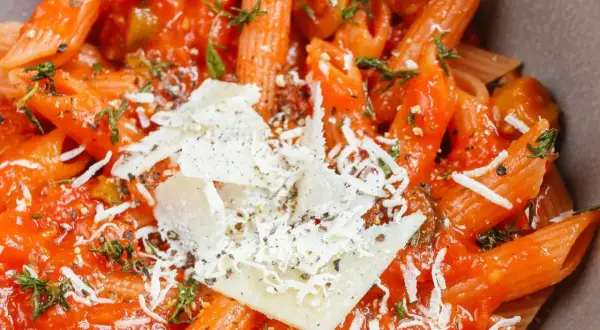 Szybki obiad z makaronem penne w sosie pomidorowym, posypany parmezanem i ziołami. Idealny na szybki posiłek.