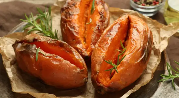 Aromatyczne bataty z piekarnika, pieczone z rozmarynem, prezentują się apetycznie na brązowym papierze.
