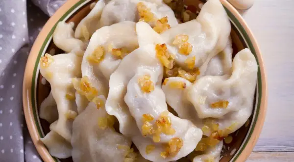 Pyszne pierogi chłopskie, okraszone skwarkami, w glinianej misie.