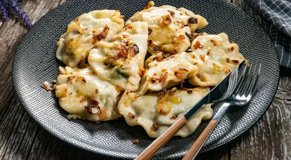 Pyszne pierogi z cebulką na talerzu. Zastanawiasz się, ile gotować pierogi, by były idealne? Te wyglądają na gotowe do jedzenia!
