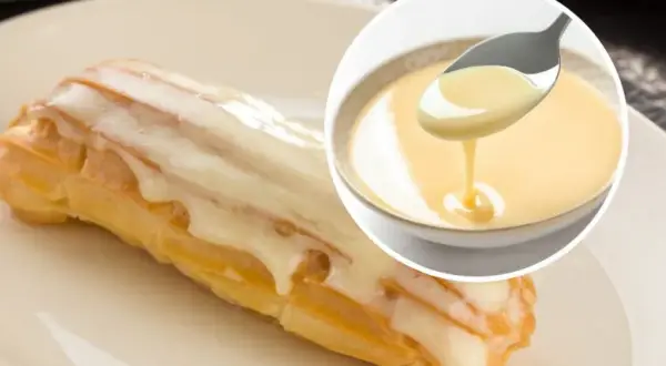Słodkie eclair oblane lukrem, obok miseczka z kremowym custard. Pyszny deser!