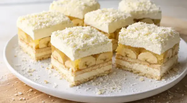 Pyszna krajanka z bananami, galaretką i bitą śmietaną, posypana wiórkami białej czekolady.