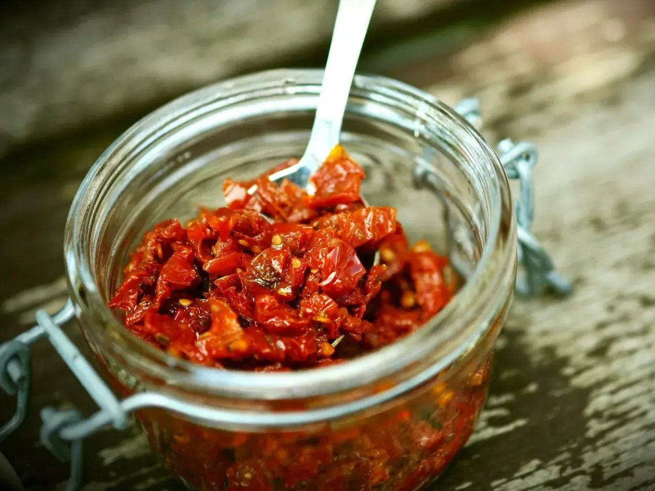 Słoik pełen aromatycznego, czerwonego pesto z suszonych pomidorów, gotowy do użycia.