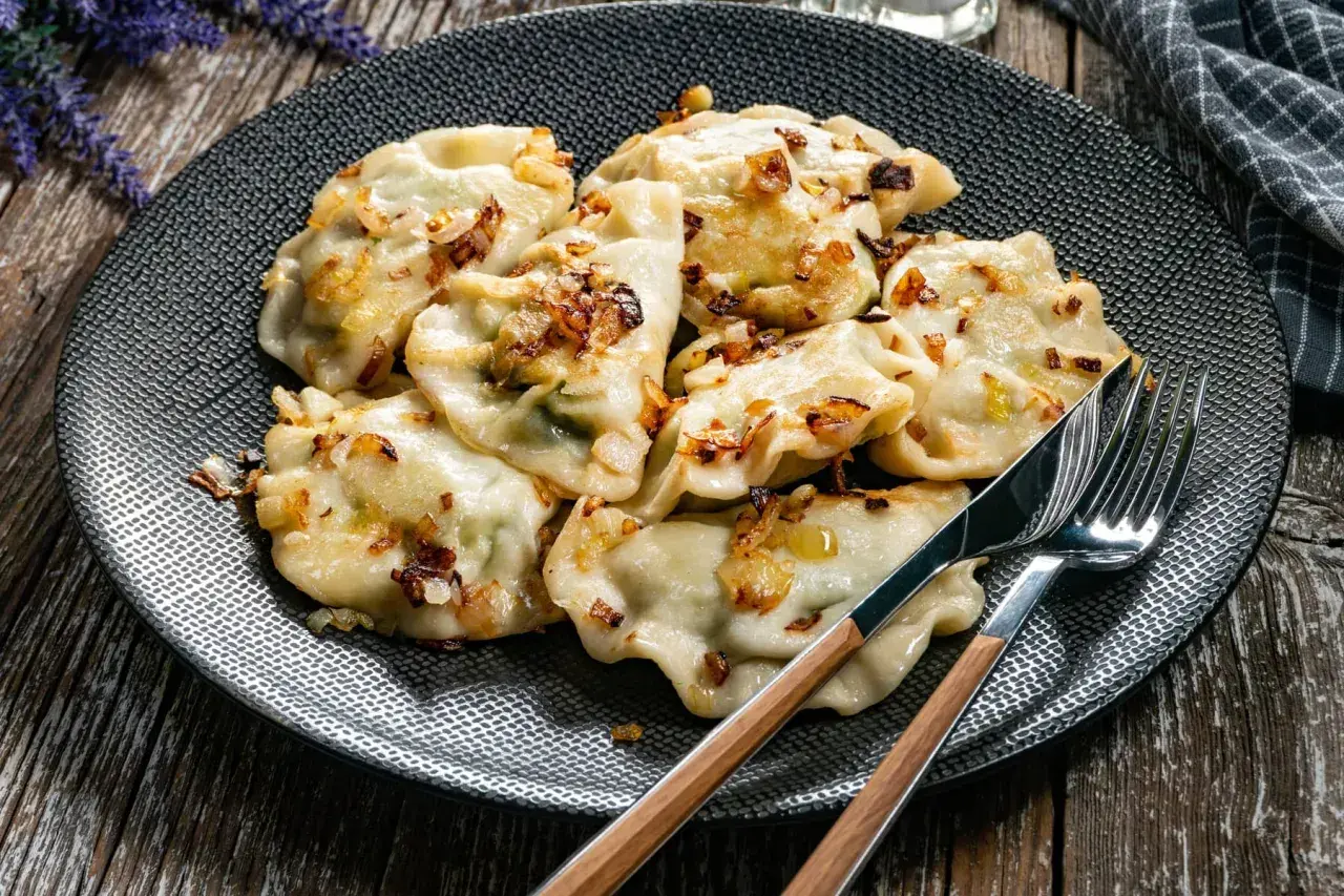 Pyszne pierogi z cebulką na talerzu. Zastanawiasz się, ile gotować pierogi, by były idealne? Te wyglądają na gotowe do jedzenia!