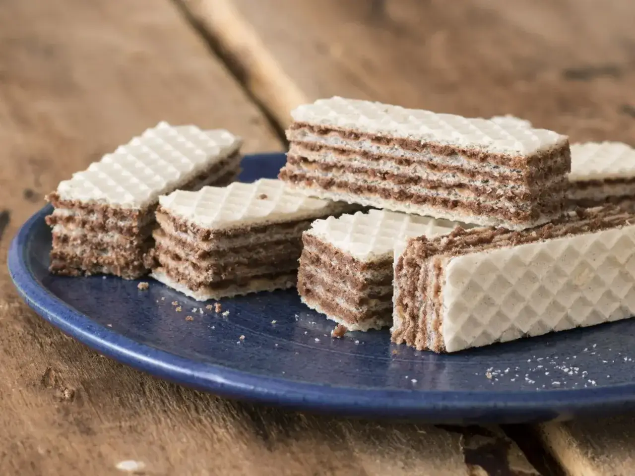 Chrupiące wafle z kremową masą kakaową, ułożone na granatowym talerzu. Idealne na deser.