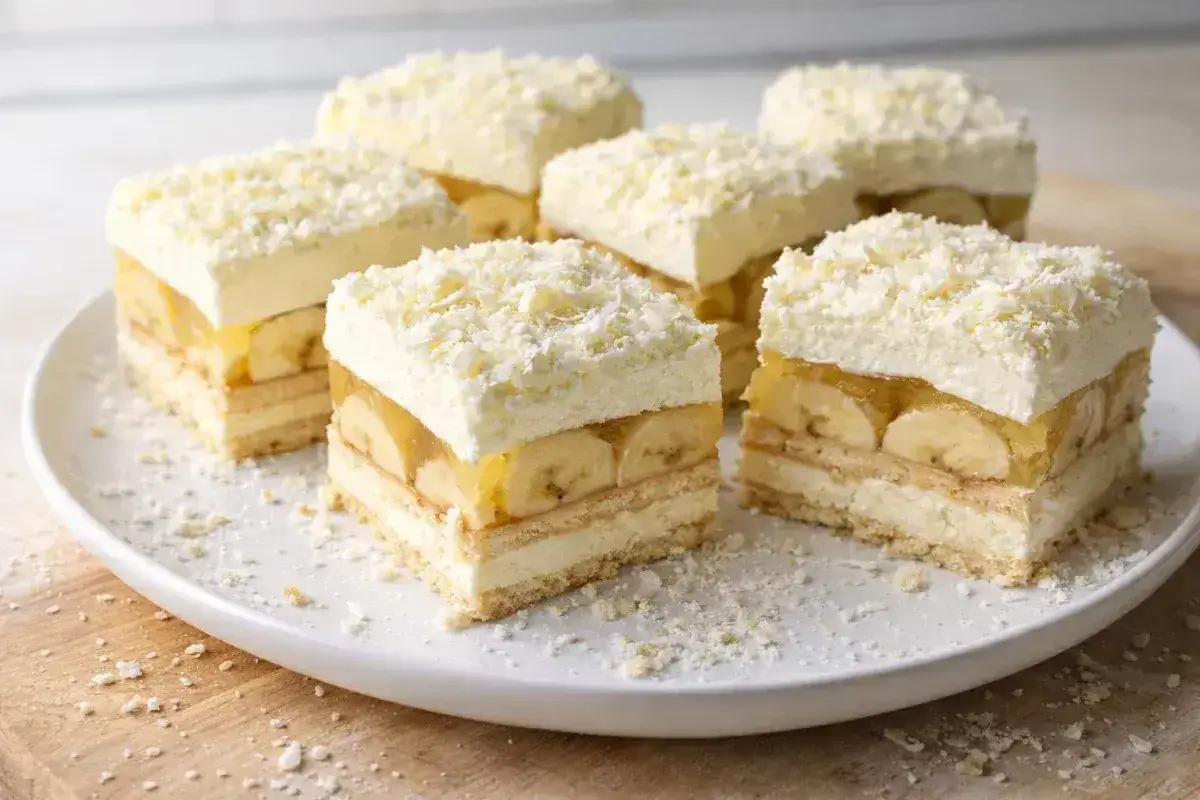 Pyszna krajanka z bananami, galaretką i bitą śmietaną, posypana wiórkami białej czekolady.