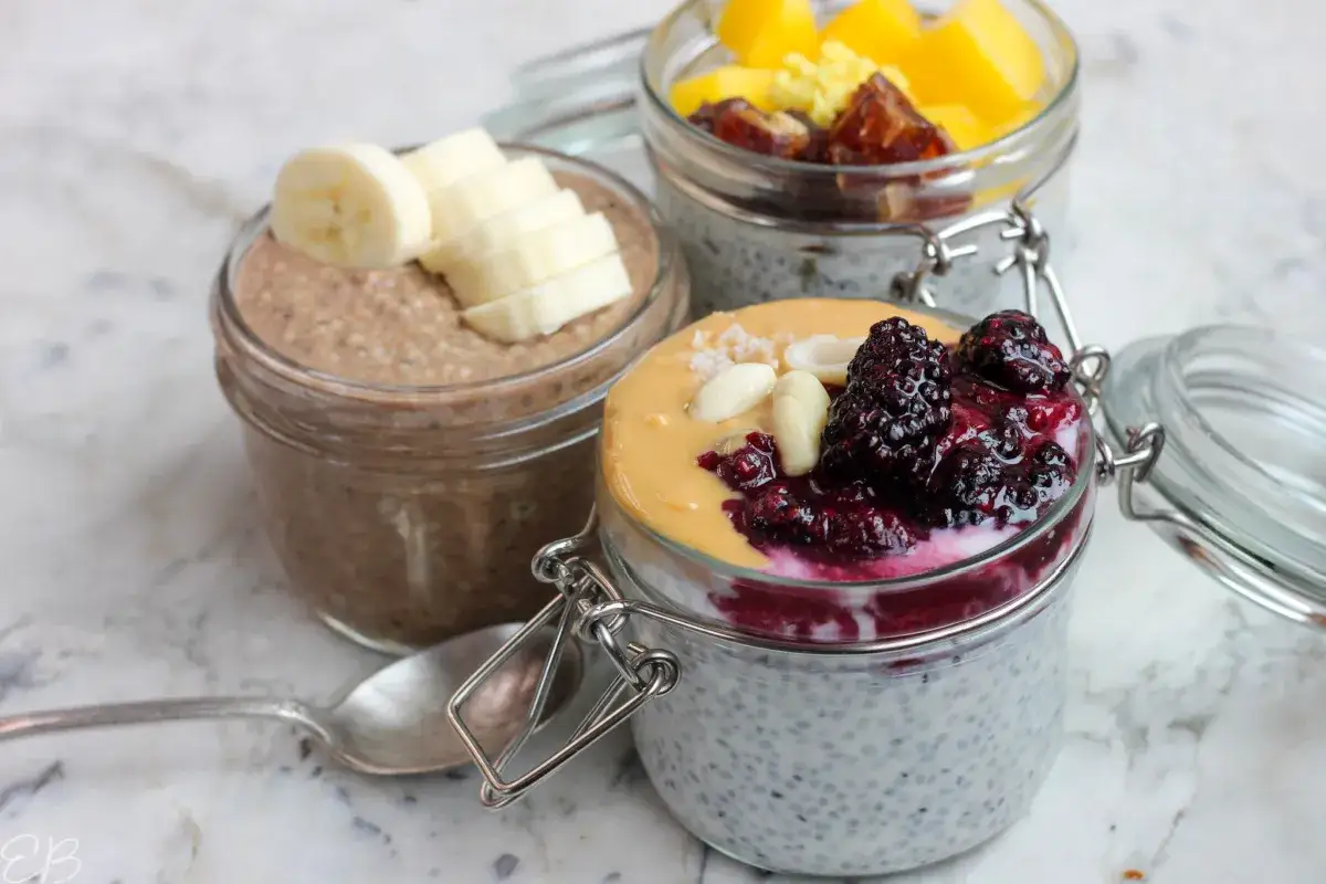 Pudding chia z owocami i masłem orzechowym. W tle deser z bananem i mango. Nasiona słodkiej bazylii tworzą bazę.