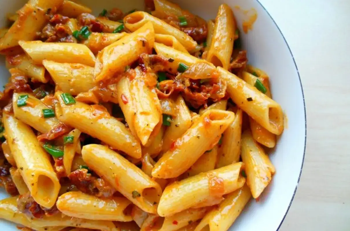 Penne z aromatycznym, czerwonym pesto, kawałkami suszonych pomidorów i szczypiorkiem.
