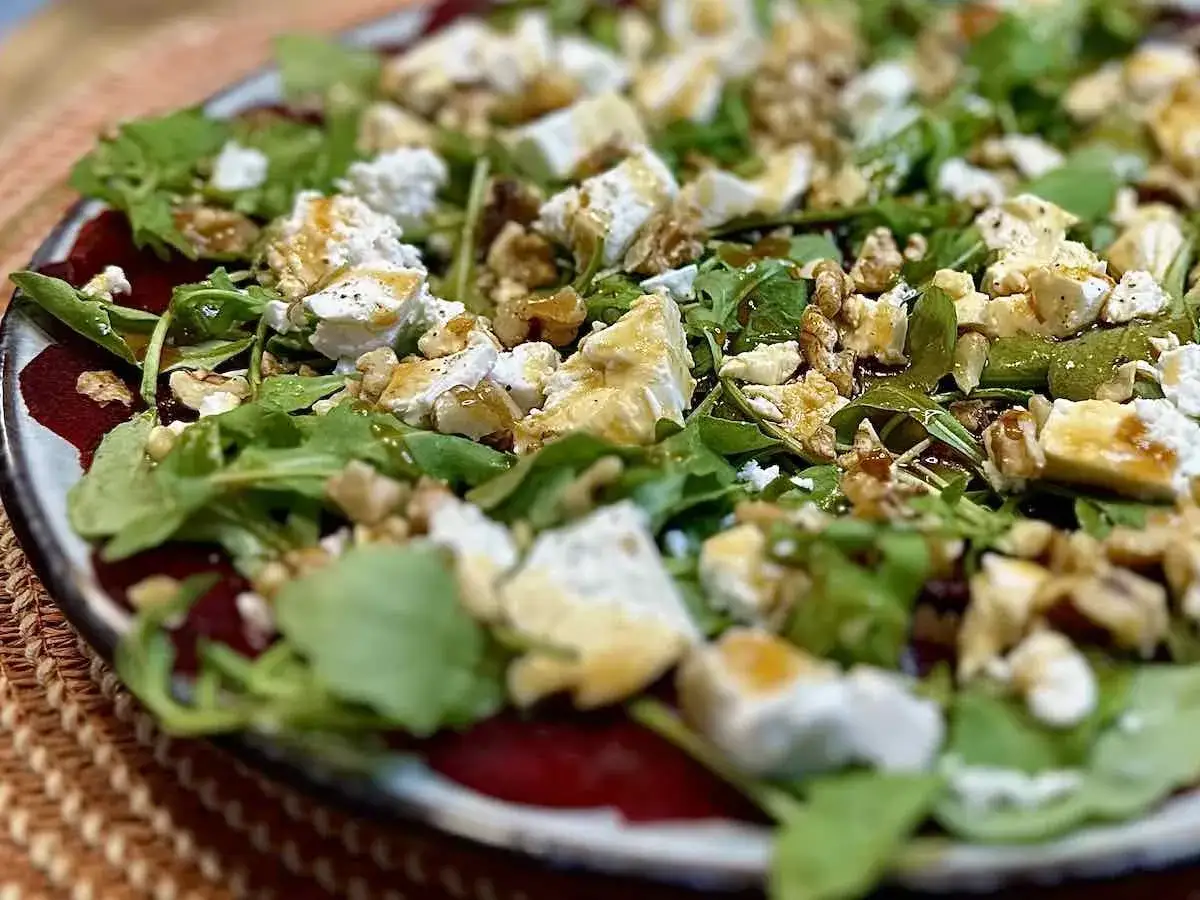 Pyszne carpaccio z buraka przepis: cienkie plastry buraka, rukola, ser kozi, orzechy włoskie i sos balsamiczny.