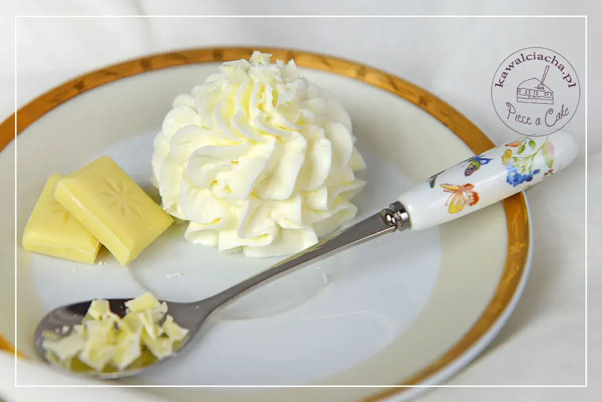 Krem z mascarpone i białej czekolady, udekorowany wiórkami, obok kostek czekolady i łyżeczki z motylami.
