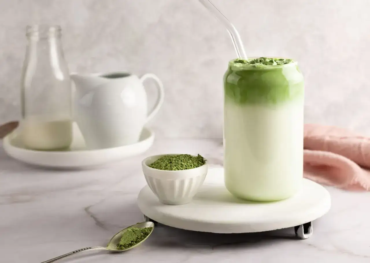 Idealny matcha latte przepis: zielony proszek matcha, mleko i gotowy napój w szklance z rurką.
