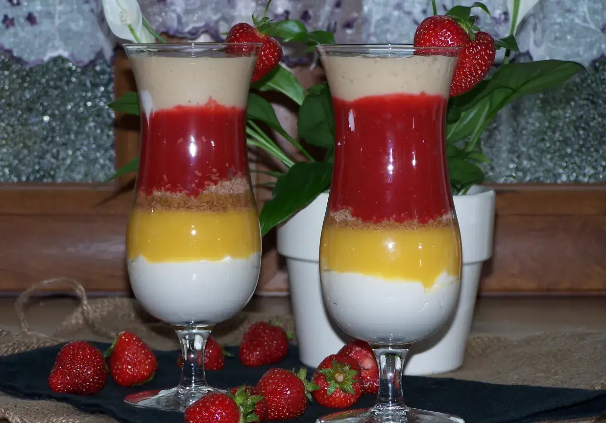Dwa puchary z warstwami owoców i kremu, w tym pyszne lody z mascarpone. Udekorowane truskawkami.