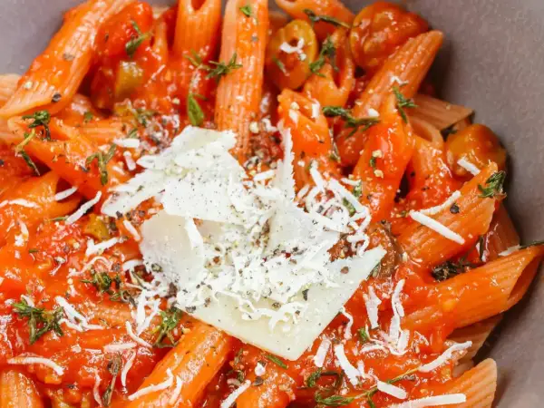 Szybki obiad z makaronem penne w sosie pomidorowym, posypany parmezanem i ziołami. Idealny na szybki posiłek.