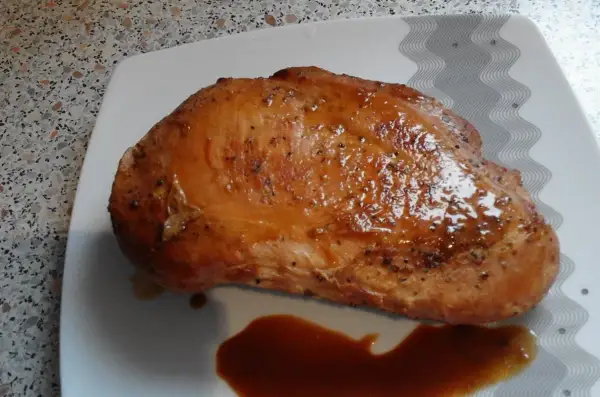 Soczysty filet z indyka w sosie własnym, przygotowany przez Anię. Danie prezentuje się apetycznie na białym talerzu.