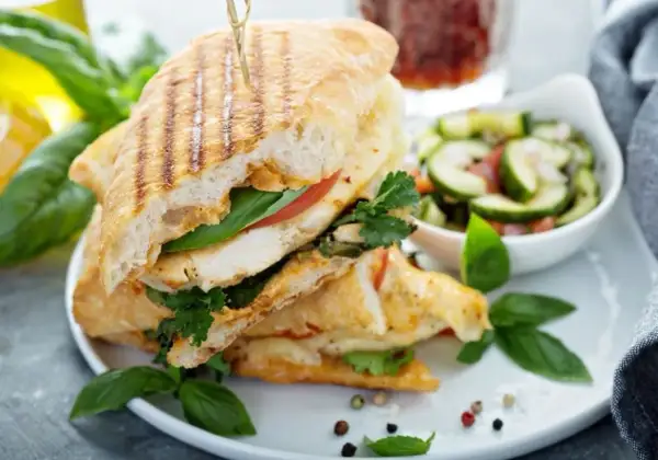 Pyszne panini z kurczakiem, pomidorem i bazylią, podane z sałatką z ogórka. Idealne na szybki lunch.