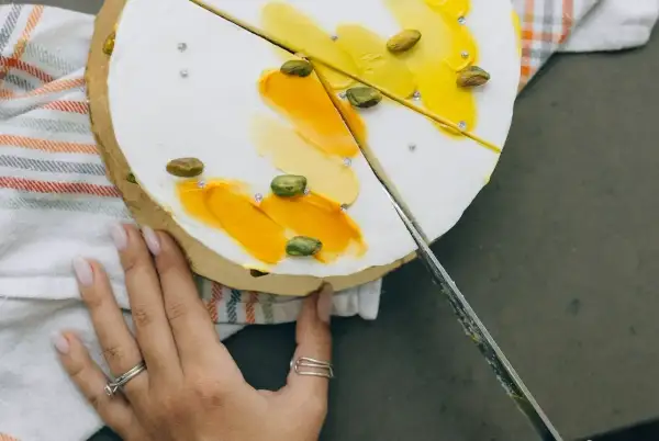 Delikatny tort z pistacjami i żółtym kremem, pokazujący, jak kroić tort, by zachować jego piękno.