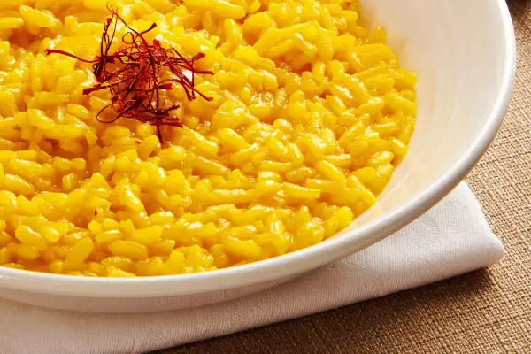 Aksamitne risotto alla milanese, bogato zdobione nitkami szafranu, kusi swoim złocistym kolorem i kremową konsystencją.