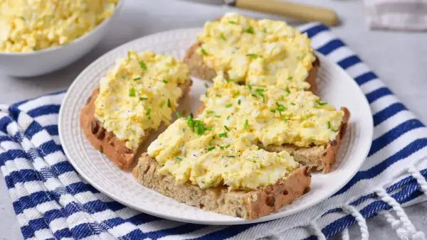 Pyszna pasta jajeczna z twarogiem na chlebie, posypana szczypiorkiem i pieprzem. Idealna na śniadanie lub przekąskę.